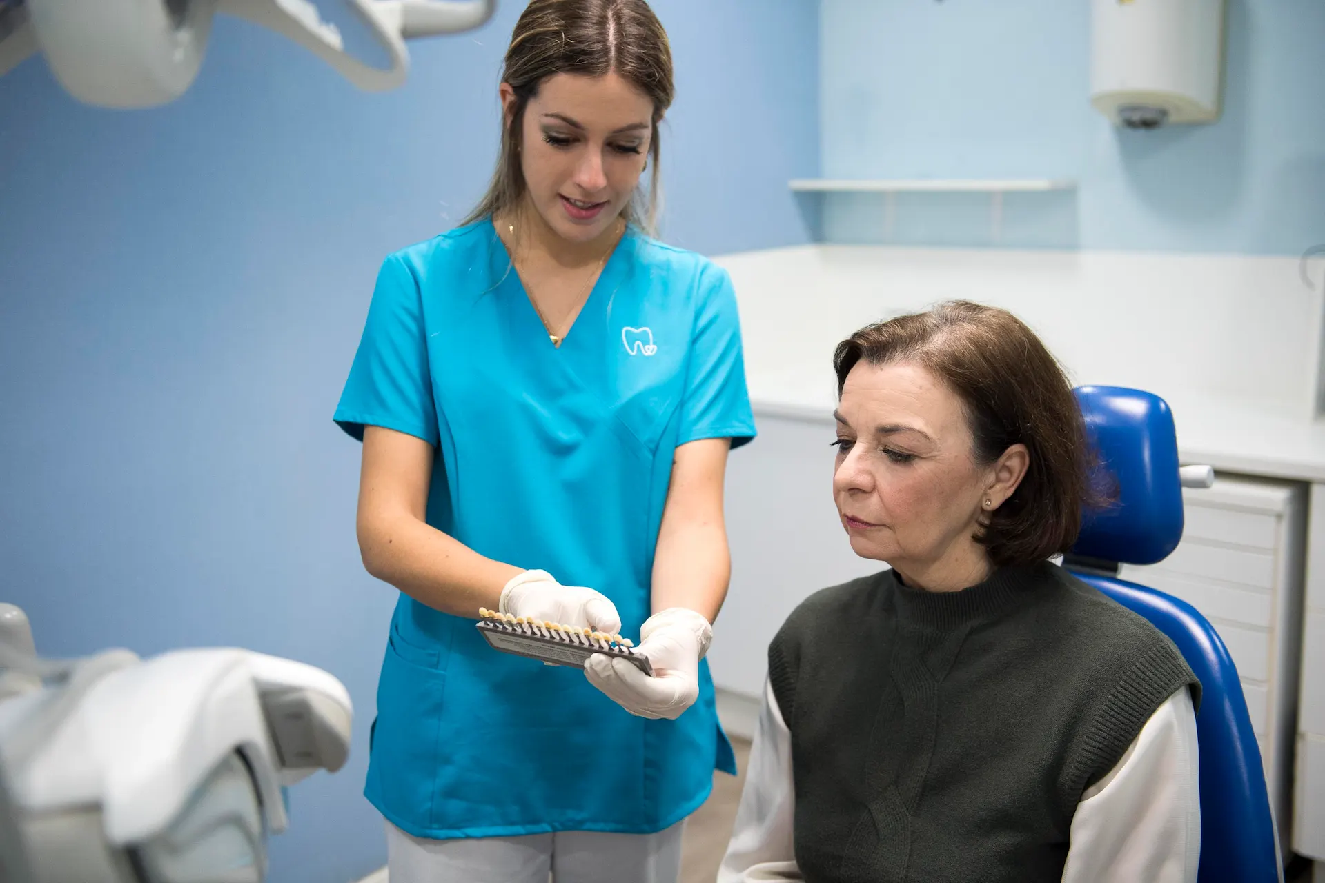 Especialista de la Clinica Dental Marilo Puchol mostrando una guia de color a una paciente